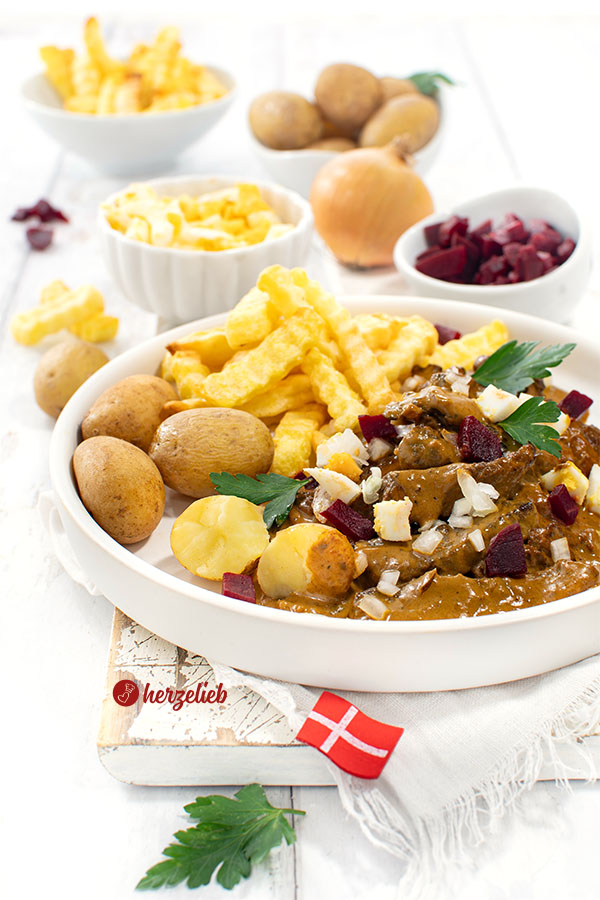 Ein Teller mit Kong Fiddes Livret. Serviert ist das Rindfleischgericht mit Kartoffeln, Pommes, Ei, Rote Bete und Zwiebeln.