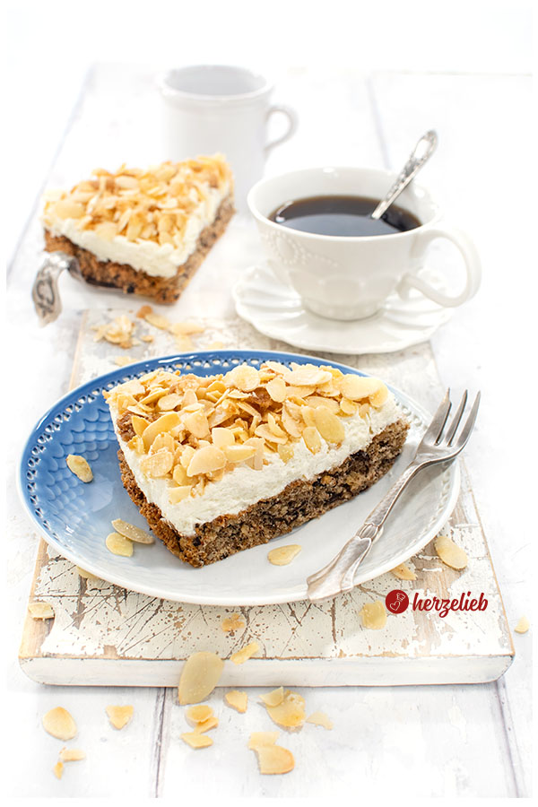 Stück Nöttårta aus Schweden auf blauem Teller mit Tasse Kaffee. Der schwedische hat Nussbiskuit unten, darauf eine Sahneschicht, oben Mandelkrokant.