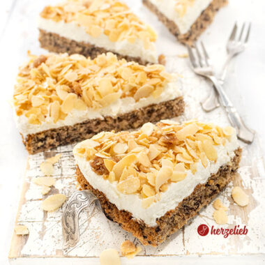 4 Stücke Nöttårta aus Schweden auf einem weißen Brett. Der schwedische hat Nussbiskuit unten, darauf eine Sahneschicht, oben Mandelkrokant.