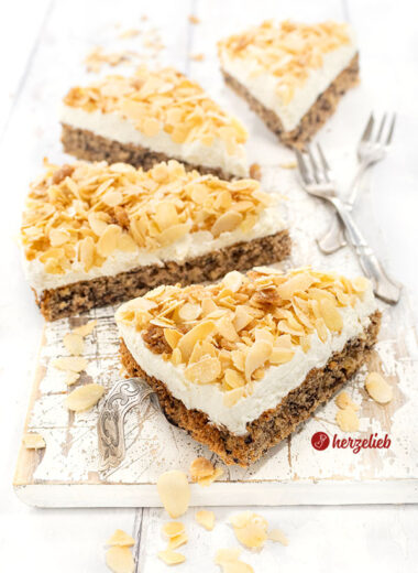 4 Stücke Nöttårta aus Schweden auf einem weißen Brett. Der schwedische hat Nussbiskuit unten, darauf eine Sahneschicht, oben Mandelkrokant.