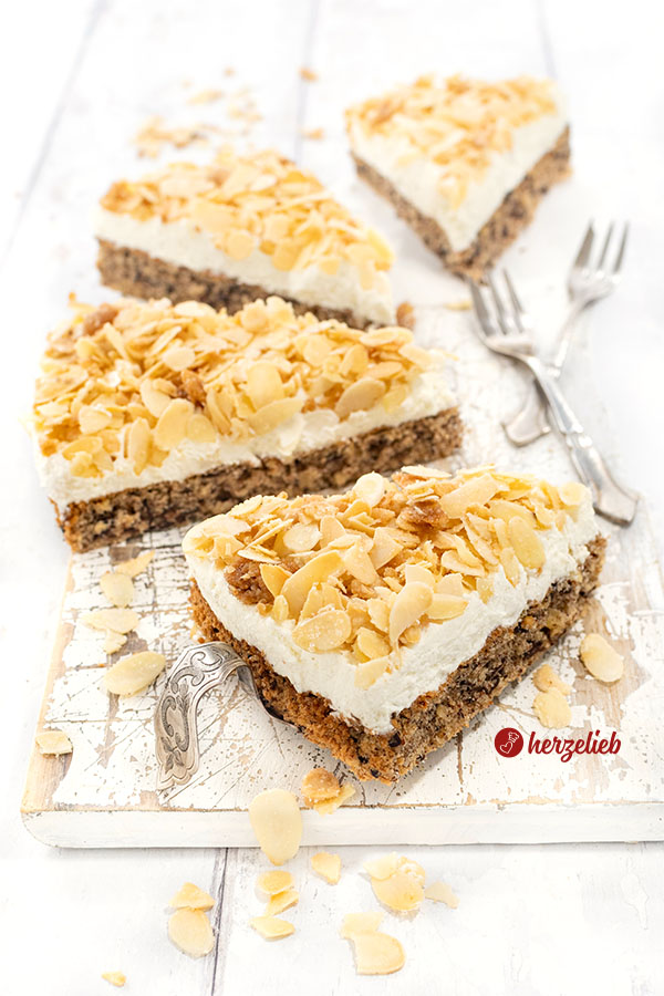 4 Stücke Nöttårta aus Schweden auf einem weißen Brett. Der schwedische hat Nussbiskuit unten, darauf eine Sahneschicht, oben Mandelkrokant. 