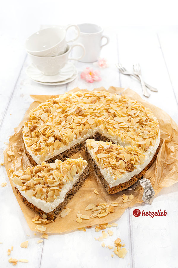 Angeschnittene Nöttårta aus Schweden auf einem Backpapier. Der schwedische hat Nussbiskuit unten, darauf eine Sahneschicht, oben Mandelkrokant. 