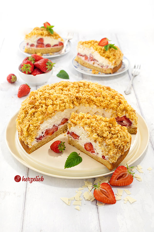 Ein angeschnittener Erdbeer-Maulwurfkuchen. Im Hintergrund je 2 Stücke davon auf Tellern