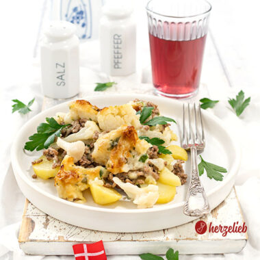 Ein Teller Samsøfad aus Dänemark mit Kartoffeln, Hackfleisch und Blumenkohl. Der Kartoffelauflauf ist dekoriert glatter Petersilie