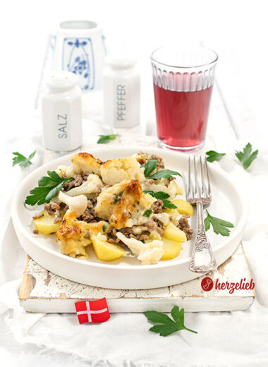 Ein Teller Samsøfad aus Dänemark mit Kartoffeln, Hackfleisch und Blumenkohl. Der Kartoffelauflauf ist dekoriert glatter Petersilie
