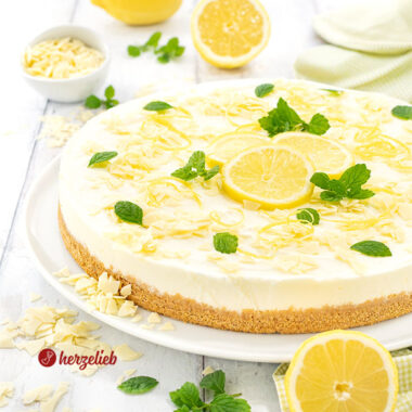 Frischer Buttermilch-Zitronenkuchen auf einem Teller. Dekoriert mit Zitronen und weißer Schokolade.