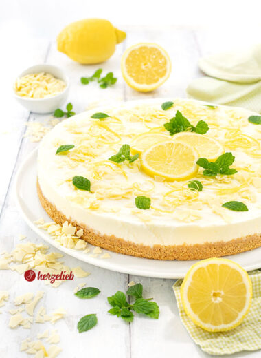 Frischer Buttermilch-Zitronenkuchen auf einem Teller. Dekoriert mit Zitronen und weißer Schokolade.