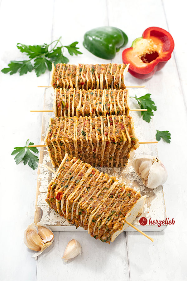 Vorbereitete Kebabspieße vor dem Backen. Dekoriert mit Petersilie und Paprika