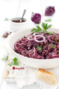 Türkischer Zwiebelsalat in einer Schüssel. Dekoriert mit Zwiebelringen und glatter Petersilie