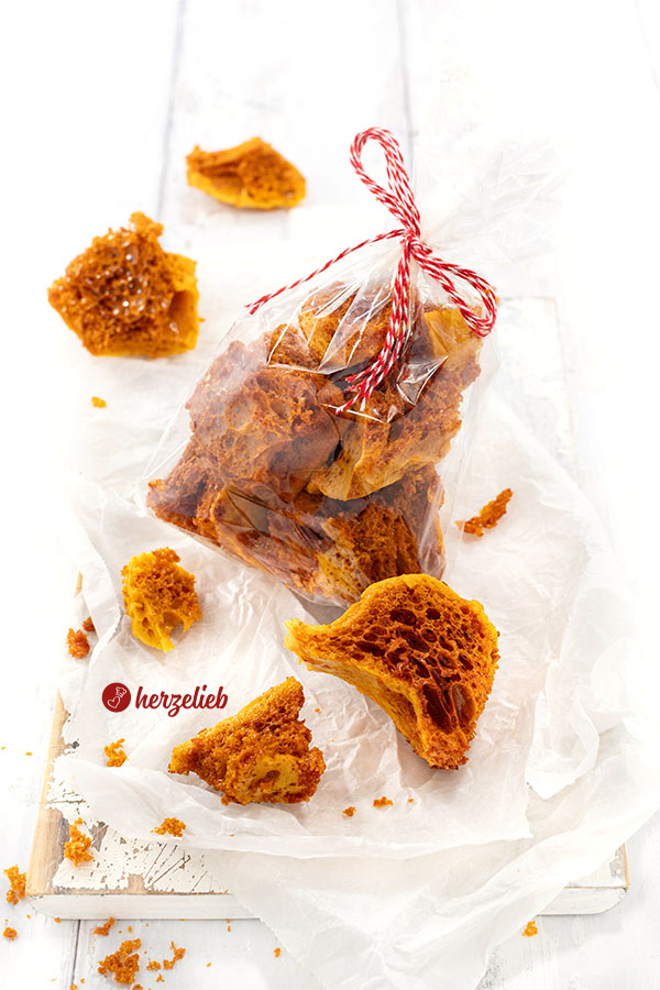 Eine Tüte Honeycomb nach einem Bienenkaramell Rezept von herzelieb. Davor und dahinter liegen einige Stücke davon.