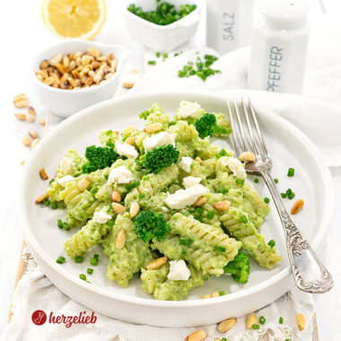 Brokkoli-Pasta mit Feta auf einem einem Teller. Dekoriert mit Fetastücken, Pinienkernen und Brokkoliröschen