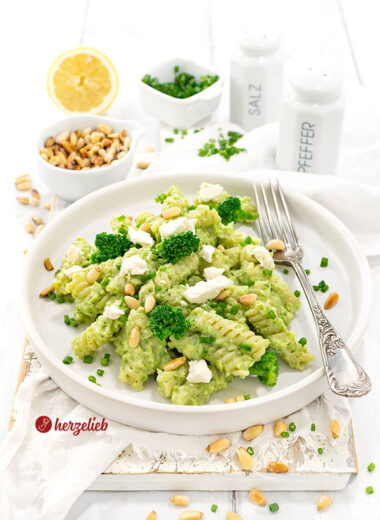 Brokkoli-Pasta mit Feta auf einem einem Teller. Dekoriert mit Fetastücken, Pinienkernen und Brokkoliröschen