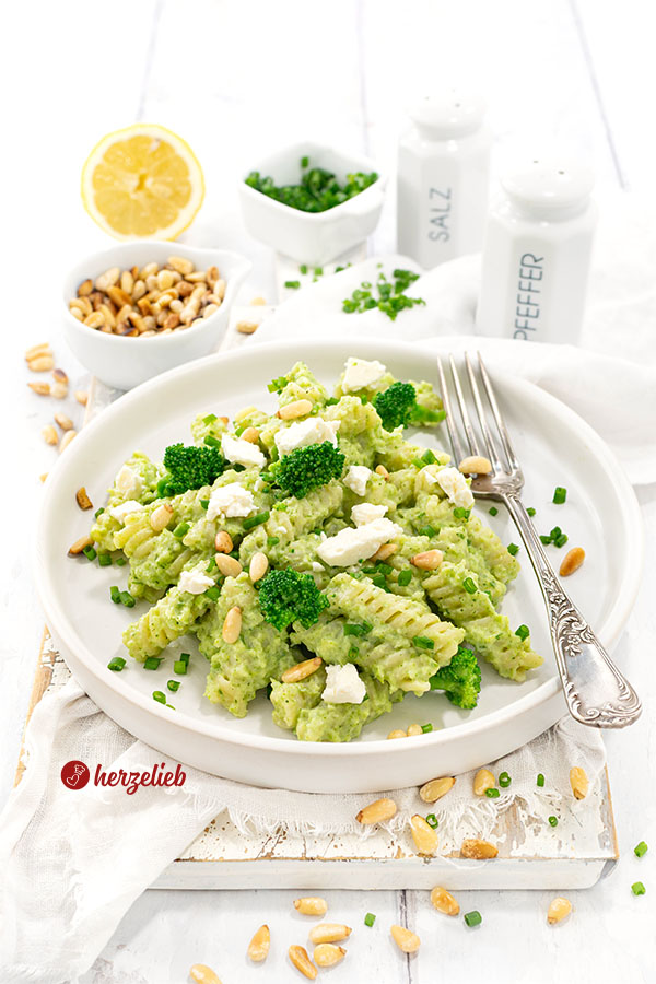 Brokkoli-Pasta mit Feta auf einem einem Teller. Dekoriert mit Fetastücken, Pinienkernen und Brokkoliröschen