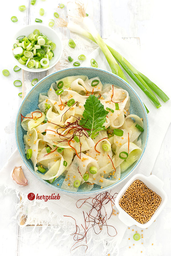 Kohlrabisalat nach einem Schüttel-Kohlrabi Rezept von herzelieb in einer schüssel. Dekoriert mit Senfsaat, Chilifäden und Frühlingszwiebeln.