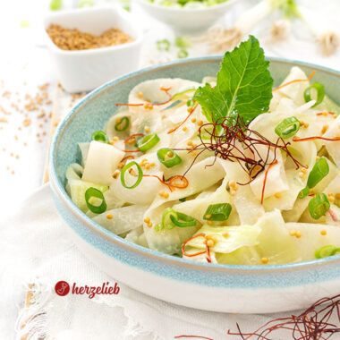 Eine Schüssel Kohlrabi-Salat nach einem Schüttel-Kohlrabi Rezept von herzelieb. Dekoriert mit einem Kohlrabiblatt, Senfsaat, Frühlingszwiebeln und Chilifäden.