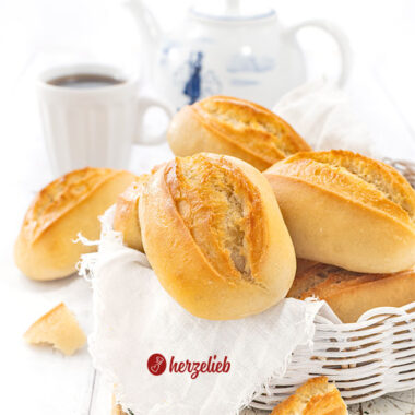 Ein Körbchen mit Brötchen nach einem Sonntagsbrötchen Rezept von herzelieb. Im Hintergrund Kaffeebecher und eine Kanne.