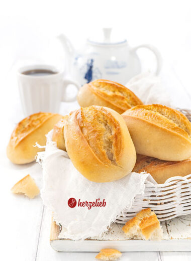Ein Körbchen mit Brötchen nach einem Sonntagsbrötchen Rezept von herzelieb. Im Hintergrund Kaffeebecher und eine Kanne.