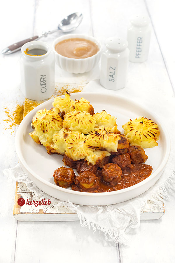 Teller mit einem Auflauf nach einem Currywurstauflauf Rezept. Der Auflauf hat eine Kartoffelhaube