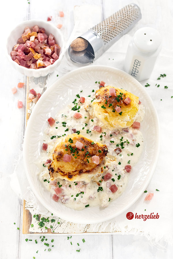Mit Käse überbackene Kartoffeln nach einem Flammkuchen-Kartoffeln Rezept von herzelieb auf einem Teller. Angerichtet mit viel heller Soße