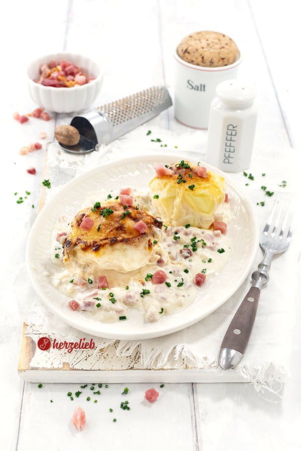 2 mit Käse überbackene Kartoffeln nach einem Flammkuchen-Kartoffeln Rezept von herzelieb. Angerichtet mit heller Soße.
