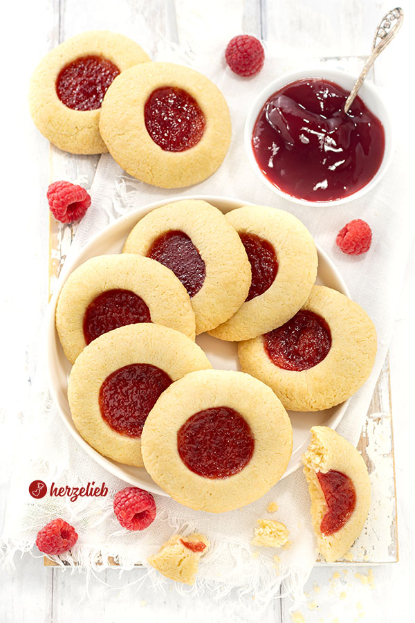 Ein Teller mit Plätzchen nach einem Hallongrottor Rezept aus Schweden von herzelieb. Angerichtet mit einer Schale Himbeermarmelade und Himbeeren.