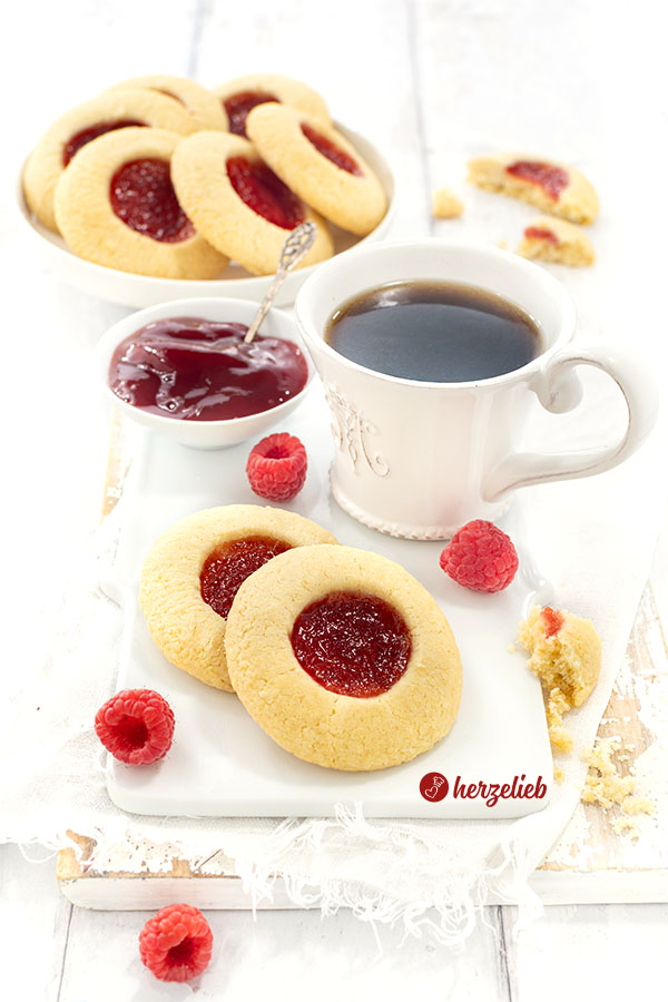 Zwei mit Marmelade gefüllte Plätzchen nach einem Hallogrottor Rezept aus Schweden von herzelieb mit einer Tasse Kaffee. Angerichtet auf einem Teller, dekoriert mit Himbeeren