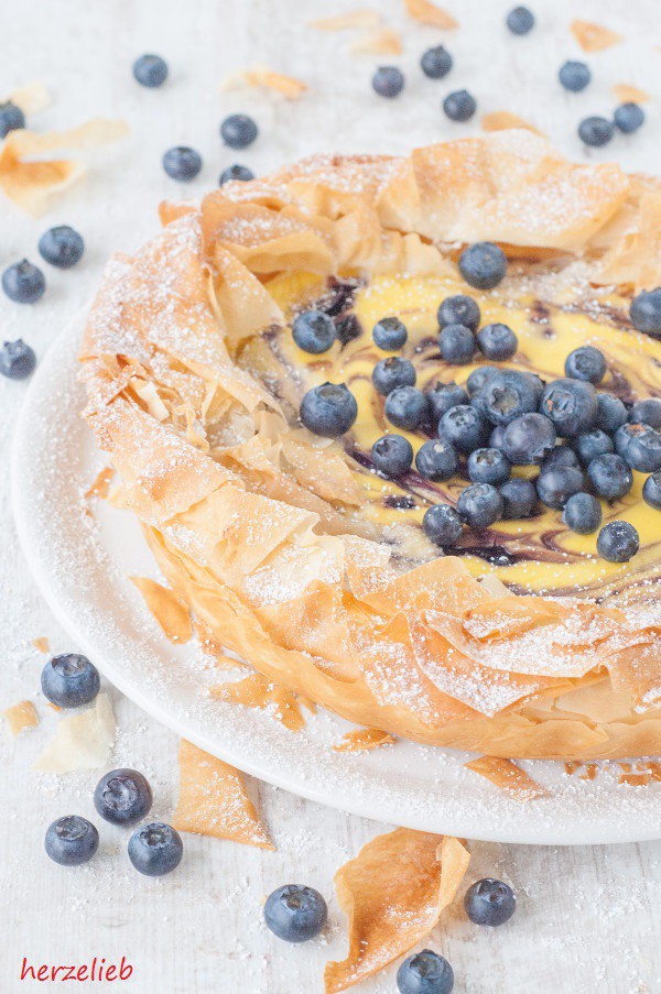 Auf diesem Bild zum Käsekuchen Rezept mit Filoteig und Blaubeeren von herzelieb sieht man den Kuchen mit seiner knusprigen Hülle, dekoriert mit Blaubeeren.